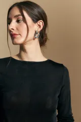 Top de manga larga con textura suave y leve brillo. Presenta una silueta al cuerpo, tajos laterales y terminaciones onduladas en el ruedo.