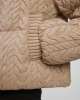 Campera puffer beige con cuello alto acanalado, cierre frontal con cremallera y bolsillos laterales.
