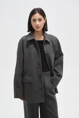 Tapado de paño color gris, con cuello camisero, cierre frontal de botones y bolsillos laterales con solapa.