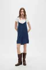Enterito corto de jean color azul índigo, con diseño holgado, escote redondo y breteles finos. Cuenta con botones decorativos en los laterales.