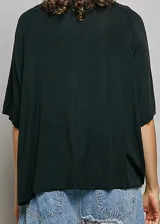 Remera básica oversize de color negro, con mangas cortas tipo raglán y un bolsillo frontal en el pecho. Presenta un corte holgado y un diseño versátil.