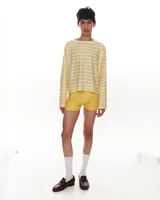 Remera de manga larga confeccionada en viscosa, con estampado de rayas horizontales amarillas y blancas, corte a la altura de la cadera y cuello con puño en algodón.