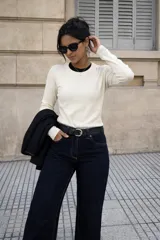 Sweater de punto fino en color crudo, con cuello redondo y mangas largas. Presenta un diseño ajustado y minimalista, ideal para usar como prenda base o sola.