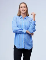 Camisa celeste con estampado de rayas verticales blancas y grises, de corte holgado, cuello con solapa y abertura central con botones. Delantera con bolsillo aplicado y mangas largas regulables con presilla y botón.