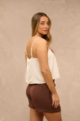 Blusa blanca de tirantes finos, con escote en V y detalles de encaje y fruncidos en el frente.