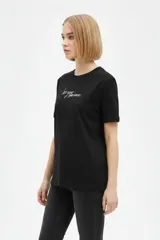 Remera negra de algodón con cuello redondo, manga corta y estampa frontal con texto en blanco.