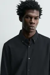 Camisa de corte relajado confeccionada en tejido ligero de lana y algodón. Presenta cuello con botones, manga larga con puños abotonados y cierre frontal de botones.