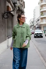Chaqueta de lana afieltrada en color amarillo mostaza, con cuello camisero, cierre frontal con broches a presión y bolsillos delanteros. Presenta un diseño de espalda con apertura para mayor movimiento.