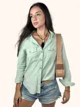 Bolso tipo baguette de cuero genuino color marrón claro, con dos compartimentos frontales con solapa y un parche de gamuza con el logo de un búho grabado. Posee una correa ancha de cuero ajustable.