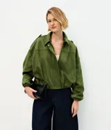 Campera bomber de gamuza sintética color verde oliva, con cuello clásico, cierre frontal, hombros caídos y puños elásticos. Presenta un diseño holgado y acabado aterciopelado.