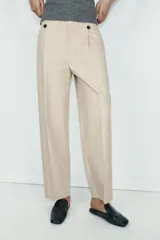 Pantalón de tiro alto con corte recto, bolsillos delanteros y detalle de pinzas con botones en la cintura. Cuenta con cierre frontal de cremallera y gancho metálico.