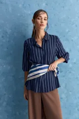 Camisa de calce relajado con cuello clásico, mangas largas con puños elastizados y rayas verticales que aportan un estilo atemporal. Su diseño liviano y versátil cuenta con estampado floral verde sobre fondo de rayas celestes y blancas.