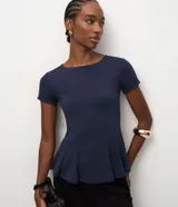 Blusa peplum Cortelle confeccionada en punto Roma color azul marino, de manga corta, escote redondo y diseño estructurado con recortes que definen la silueta y ruedo acampanado.