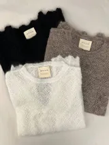 Sweater de punto calado confeccionado en 100% mohair italiano, con cuello redondo y mangas largas. Presenta una textura aireada y delicada con un diseño etéreo y sofisticado.