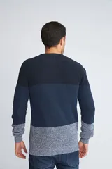 Sweater de punto con diseño color block en tonos azul marino y gris jaspeado. Presenta cuello redondo, mangas largas y un ajuste regular.