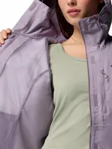 Campera impermeable Columbia modelo Hikebound II, color violeta. Cuenta con capucha ajustable, cierre frontal con solapa, bolsillos con cremallera en el pecho y laterales, y puños ajustables. Diseñada con tecnología Omni-Tech para mayor protección contra la lluvia.