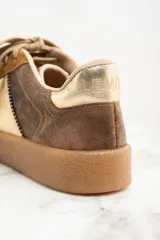 Zapatillas deportivas de cuero color marrón con detalles en dorado y suela color caramelo.