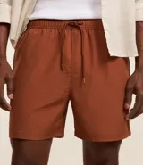 Bermuda de baño color beige, confeccionada en tejido ana ruga texturizado. Tiene lazo en la cintura, bolsillos laterales y un bolsillo trasero.