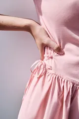 Vestido corto negro confeccionado en 100% algodón, de cuello redondo y mangas cortas. Presenta detalle de lazadas en los laterales de la cintura y falda con vuelo.
