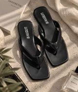 Sandalias planas tipo chancleta con base marrón de punta cuadrada y tiras anchas en color blanco.