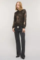 Camisa de satén con estampado animal print tipo leopardo en tonos marrones y negros. Presenta cuello alto con volados, mangas largas con puños abotonados y detalles de volados fruncidos a lo largo de la botonadura frontal.