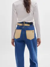 Pantalón jean de tiro alto y corte pinzado, con perneras de caída suelta y levemente anchas en el bajo. Posee pasador con hebilla en la parte trasera.