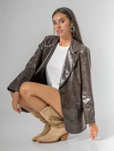Blazer de mujer color marrón chocolate, confeccionado en ecocuero texturizado con acabado acharolado. Es forrado y presenta un corte estructurado con solapas y bolsillos frontales.