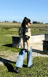 Blusa de lino color marrón oscuro con cuello alto, alforzas decorativas en el frente, mangas abullonadas y puños con botones. Presenta cierre de botones a la vista en la espalda.