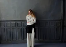 Blusa de manga larga en color crema, con cuello alto y diseño de drapeado suave en la parte frontal. Presenta un corte recto y elegante.
