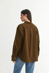 Camisa marrón de pana fina con cuello solapa clásico, bolsillo cuadrado en el pecho, botones personalizados y calce oversize.