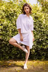 Minifalda blanca de lino bordado, con cintura elastizada en la espalda, cinto decorativo y tablas laterales.