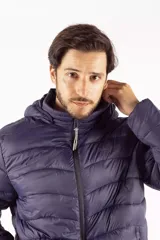 Campera puffer de hombre color azul oscuro, con diseño acolchado, cierre frontal completo, bolsillos laterales con cierre y capucha desmontable. Presenta logo de la marca estampado en el pecho y en la manga.