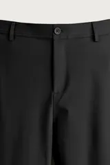 Pantalón regular fit de hombre color negro, confeccionado en tejido técnico ligero con cintura elástica, bolsillos frontales, bolsillos traseros de vivo y cierre frontal con cremallera y botón.