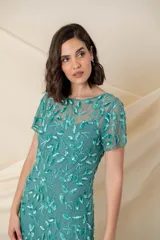 Vestido largo de tul verde con bordado floral al tono, corte sirena y mangas cortas.