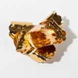 Aros colgantes dorados con forma de flor con textura irregular.