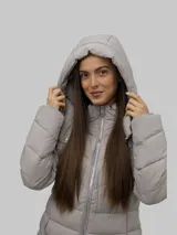 Campera puffer color gris, con cuello alto y capucha desmontable. Cierre frontal con cremallera y bolsillos laterales con cierre. Diseño acolchado y detalles distintivos de Calvin Klein.