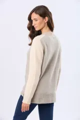 Saco tipo cárdigan de tejido grueso con diseño en bloques de color, combinando tonos beige y rosado. Presenta cuello en V, cierre frontal con botones y dos bolsillos delanteros.