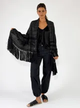 Pashmina de punto color beige con bordados sutiles y flecos largos en los bordes.