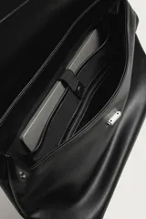 Bolso de mano y hombro color negro, con diseño estructurado, solapa frontal y cierre metálico. Cuenta con asa superior de mano y un compartimento principal amplio.