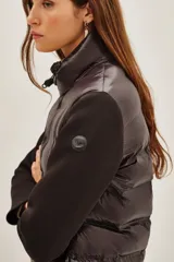 Campera híbrida con frente acolchado tipo puffer en color negro y mangas de tejido liso al tono. Presenta cuello alto, cierre frontal y diseño entallado.