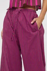 Pantalón de tiro medio con estampa a rayas en tonos fucsia y marrón oscuro, cintura elástica con cordón ajustable, bolsillos laterales y silueta amplia de corte recto.