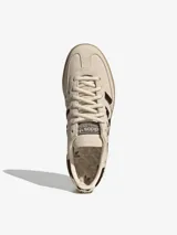 Championes Adidas Handball Spezial de diseño clásico, confeccionados en gamuza color crema con detalles de estampado animal print en las icónicas tres tiras y el talón. Presentan suela de goma color caramelo y logo dorado en el lateral.