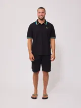 Chomba negra de corte regular, con cuello y mangas con rayas en contraste color verde y amarillo.