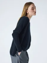 Sweater tejido de calce holgado con escote en V, mangas largas y tajos laterales en el ruedo. Presenta un diseño minimalista con detalle a contratono en la espalda.
