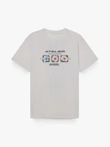 Remera de corte oversize, color blanco, con cuello redondo y mangas cortas. Presenta una estampa frontal con el texto 'ATELIER (UNVEILING VISIONS)' y tres recuadros con ilustraciones de flores.