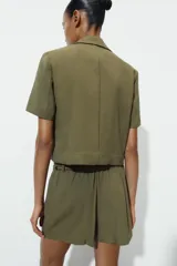 Bermuda de tiro alto en color verde militar, con cintura elástica y detalle de cinturón fino trenzado con abalorios decorativos.