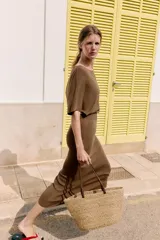 Bolso tipo shopper confeccionado en yute trenzado, con doble asa de mano en cuero sintético color marrón.