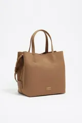 Bolso tote grande de color marrón, con asas de mano y asa bandolera regulable de tejido. Presenta un parche con el logo de Bimba y Lola en dorado en el frente.