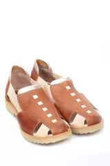 Zapato tipo sandalia plana de cuero liso en color rojo cereza con detalles en color crema. Presenta paneles laterales elásticos, suela dentada y diseño con aberturas.