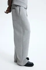 Pantalón tipo jogger de corte relajado con efecto neopreno, cintura elástica con cordón ajustable, bolsillos laterales al bies y bolsillo trasero de parche.